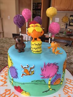 a birthday cake decorated with sesame street characters and lollipops on the top