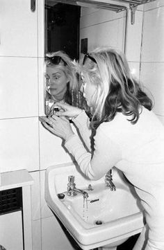 two women standing in front of a mirror brushing their teeth and looking into the mirror