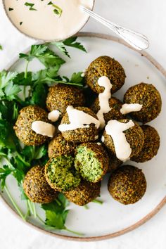 a white plate topped with falafel next to a bowl of ranch dressing