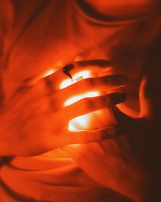 a person holding their hand in front of an orange light that is shining on them