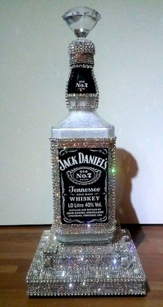 a bottle of jack daniels whiskey sitting on top of a glass stand with diamonds around it