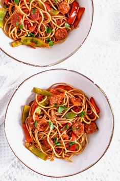 two white bowls filled with spaghetti and vegetables