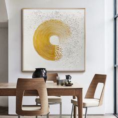 a dining room table with two chairs and a large painting on the wall above it