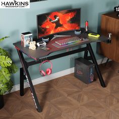 a computer desk with headphones on it in front of a blue wall and wooden floors