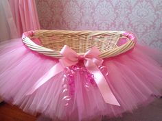 a pink tutule and bow sits in a wicker basket on the floor