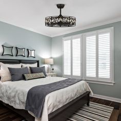 a bedroom with blue walls and white shutters on the window sill above the bed