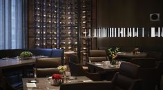 an empty restaurant with tables and chairs in front of a wine rack wall filled with bottles