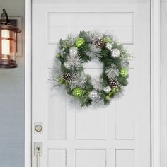 a white door with a wreath on it and a light hanging from the side wall