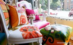 a room filled with lots of colorful furniture and pillows on top of each other in front of a window