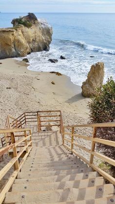 stairs lead down to the beach with rocks in the background