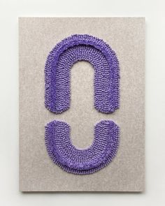 the letter u is made out of purple yarn and sits on top of a white surface