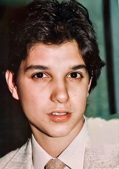 a young man in a suit and tie looking at the camera with an intense look on his face