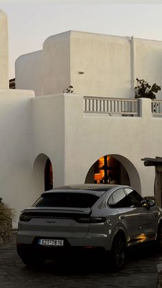 a car parked in front of a white building with an orange light at the entrance