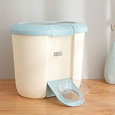 a blue and white ice bucket sitting on top of a wooden table next to a vase