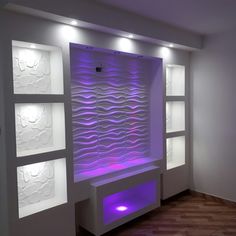 an empty room with white walls and purple lighting on the wall, along with shelves