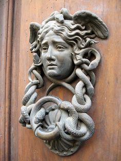 a statue of an angel with snakes around it's neck on a wooden door