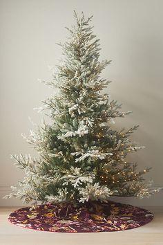 a small white christmas tree in a room with a rug on the floor and a wall behind it