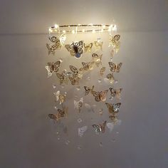 a wall mounted light with butterflies hanging from it's sides and some lights on the side