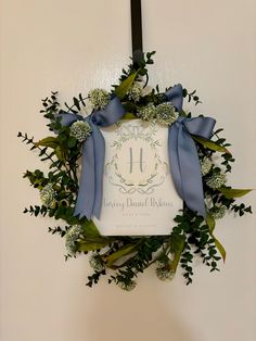 a wreath hanging on the wall with blue ribbon