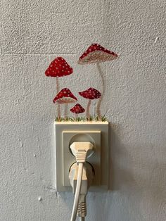 an electrical outlet with three red mushrooms on it