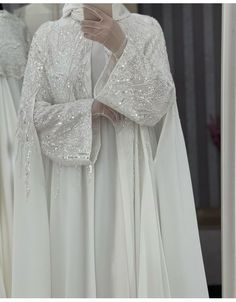 a white dress with sequins on the shoulders and sleeves is displayed in front of a mirror