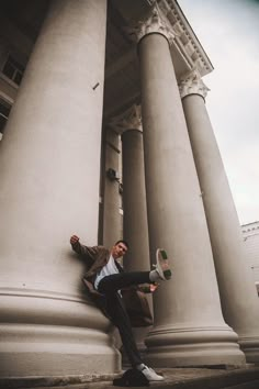 a man leaning against the side of an old building with his leg up on a pillar