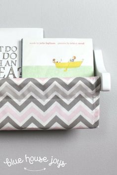 a gray and white chevroned tray with books in it, sitting on a wall