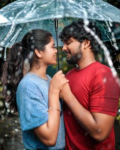 a man and woman standing under an umbrella in the rain, looking into each other's eyes