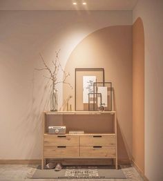 a wooden dresser sitting in front of a mirror on top of a wall next to a vase