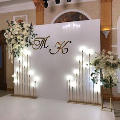 the backdrop is decorated with white flowers and greenery, along with gold poles that hold candles