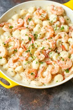 a yellow skillet filled with shrimp and macaroni on top of a table