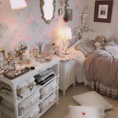 a bedroom with white furniture and pink flowers on the wall, along with other decorations