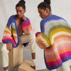 a woman sitting on top of a box wearing a colorful sweater