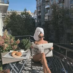 a woman sitting on a balcony reading a newspaper