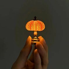 a person is holding a small lamp in their hand, with the light turned on