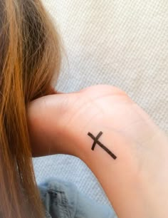 a woman with a small cross tattoo on her left hand