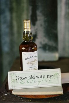 a bottle of wine sitting on top of a table next to a sign that says grow old with me