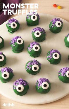 green and purple monster truffles on a white plate with candy candies in the shape of eyes