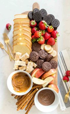 a wooden platter filled with crackers, cookies and fruit on top of a table