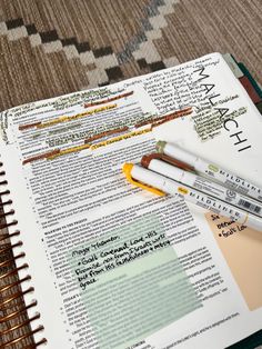 two pens are sitting on top of an open book that is filled with words and phrases