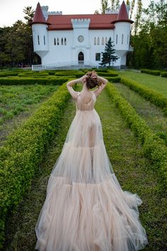 a woman in a long dress is walking through the grass