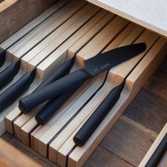 knives are sitting in a drawer on a wooden table