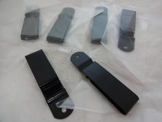 four pieces of black plastic sitting on top of a white sheet with scissors and other items