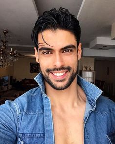 a man with no shirt is smiling at the camera while wearing a denim jacket and jeans