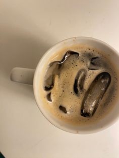 a white cup filled with liquid on top of a table