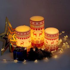 three lit candles sitting on top of a table next to christmas decorations and a star