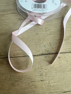 a spool of pink satin ribbon on a wooden table with a barcode attached to it