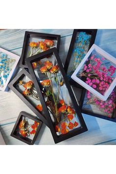 four framed pictures with flowers in them on a table