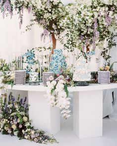 a table topped with lots of white and blue cake next to flowers on top of it