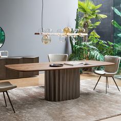 a modern dining table with chairs around it and plants on the wall in the background